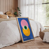 Bauhaus plakat med farverige geometriske former, placeret i et moderne soveværelse med træpaneler og naturligt lys.