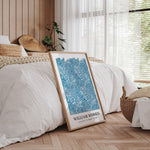 William Morris plakat i træramme, placeret på gulvet i et soveværelse med træpaneler og naturligt lys.