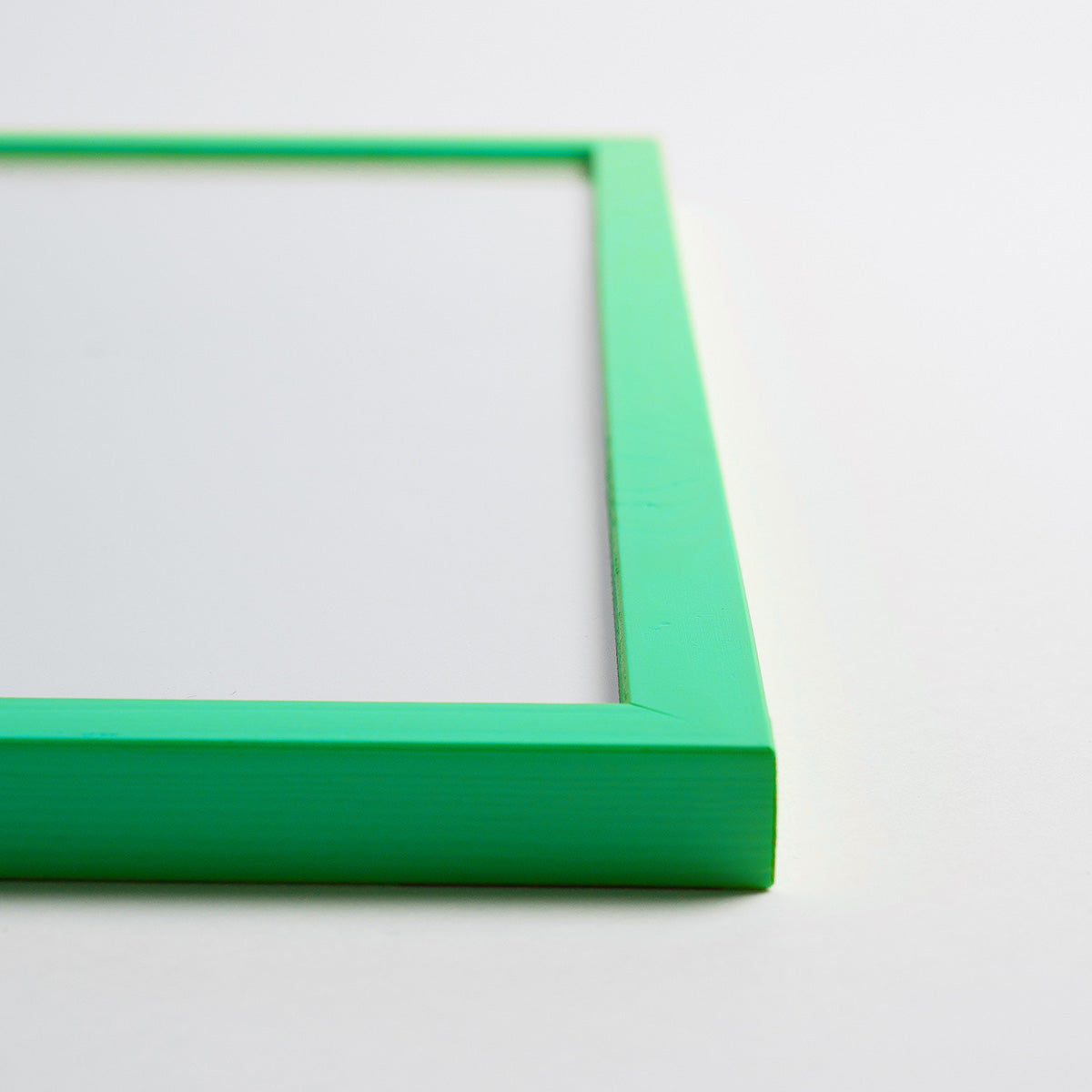 Grøn billedramme i træ, set fra siden, med en minimalistisk og moderne stil.