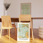 Plakat af William Morris med titlen "St James" placeret i en moderne stue med træmøbler og en plante i baggrunden.