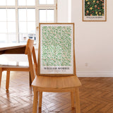 Plakat af William Morris med titlen "Willow Bough" placeret på en stol i et lyst rum.