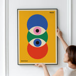 Plakat med Bauhaus-design fra 1923, viser geometriske former i blå, grøn og rød på gul baggrund, hængt op på en væg.
