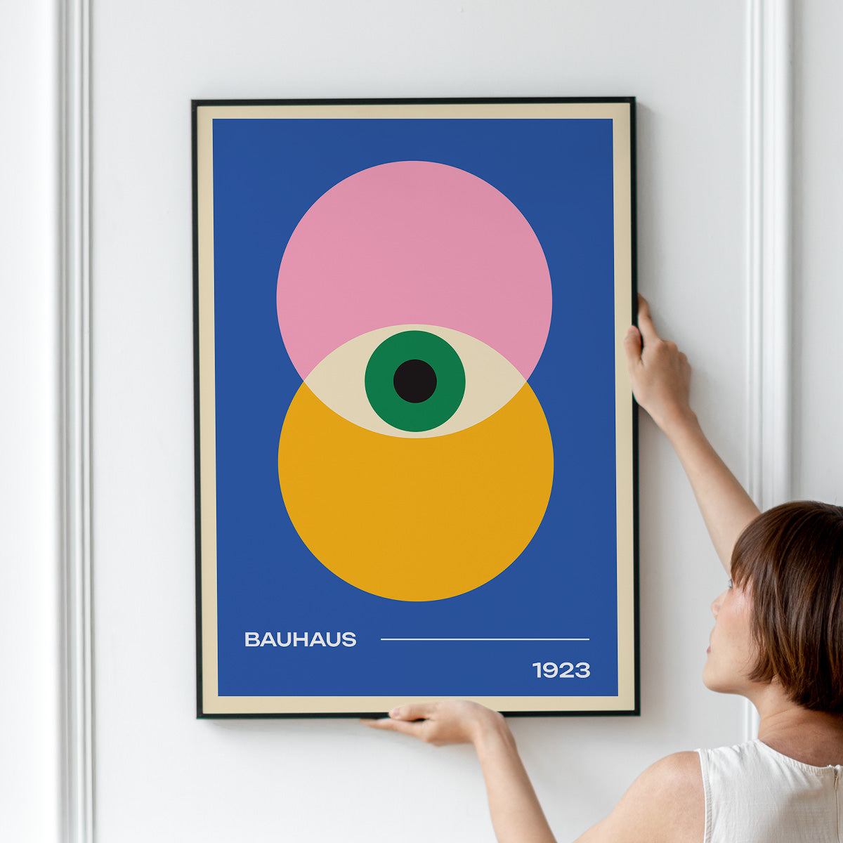 Plakat med Bauhaus-design fra 1923, viser geometriske former i pink, gul og blå med et centralt øje.