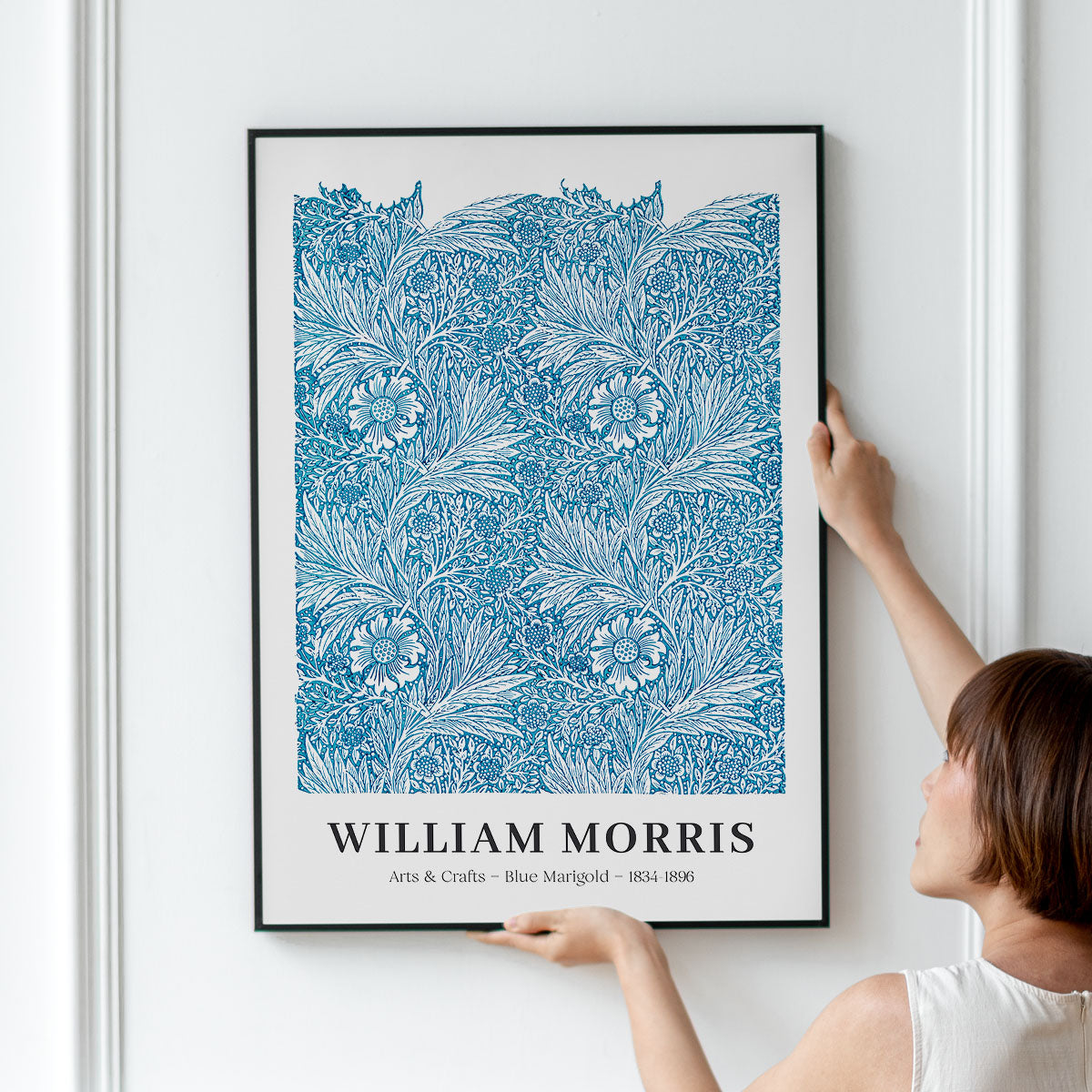 Plakat med blåt blomstermønster af William Morris, kaldet "Blue Marigold", hænges op på en væg.