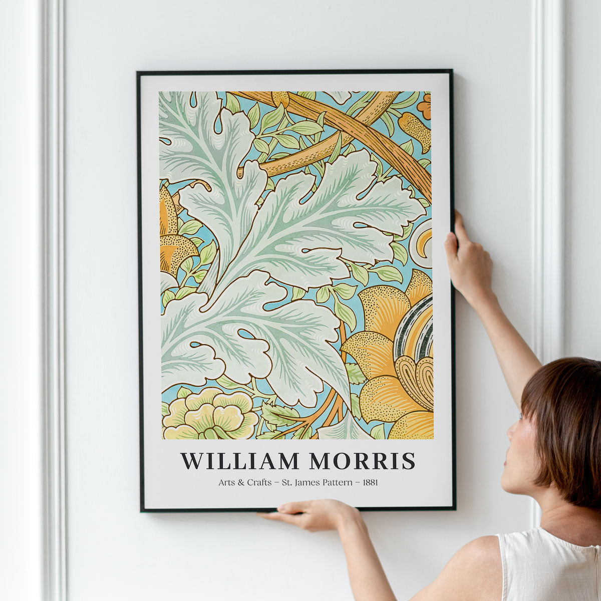 Person hænger en William Morris plakat med St. James mønster på en væg.