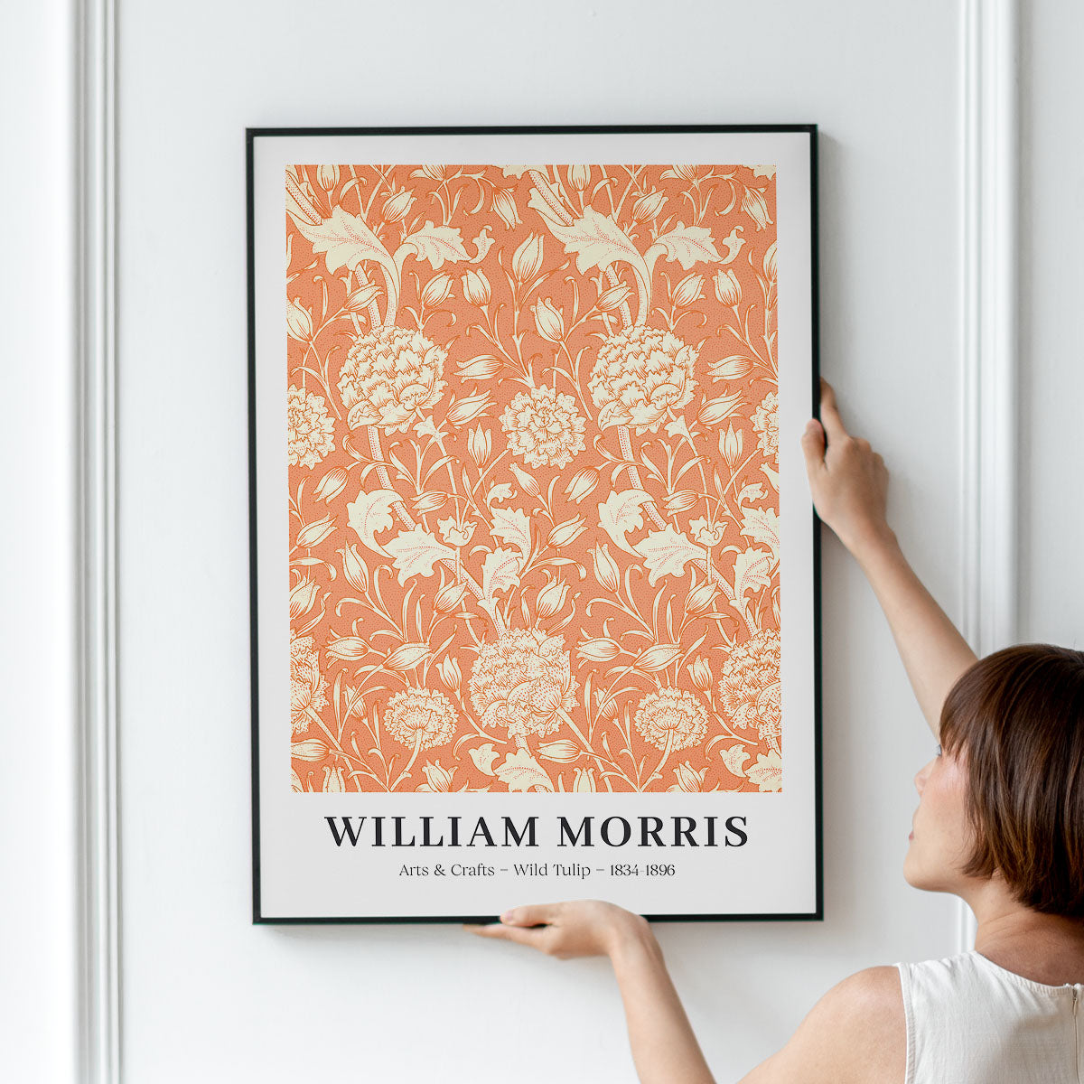 Plakat med William Morris' design "Wild Tulip" i orange og hvid, hængt op på en væg.