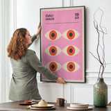 Kvinde hænger en Bauhaus-plakat med øjenmotiv på en væg i en stilfuld stue.