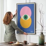Kvinde hænger en farverig Bauhaus-plakat op på en væg i en stilfuld stue.