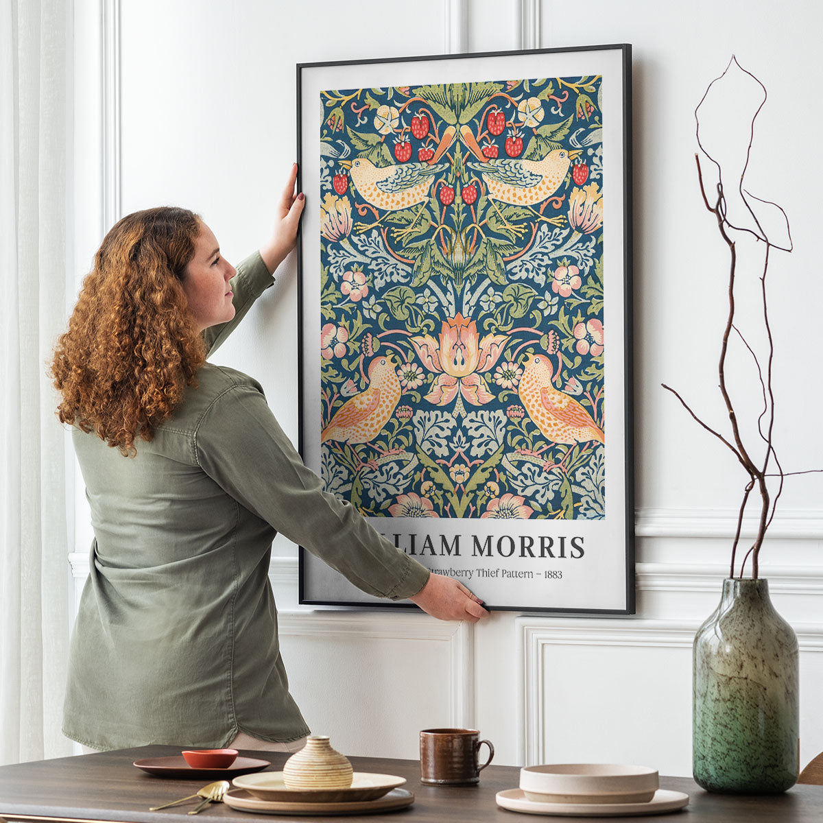 William Morris plakat med "Strawberry Thief" mønster, hængt op på en væg i en stue.