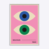 Bauhaus plakat med to stiliserede øjne i blå og grøn på lyserød baggrund, indrammet i hvid træramme.