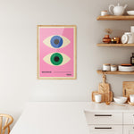 Plakat i træramme i køkken med Bauhaus-design, lyserød baggrund og to stiliserede øjne.