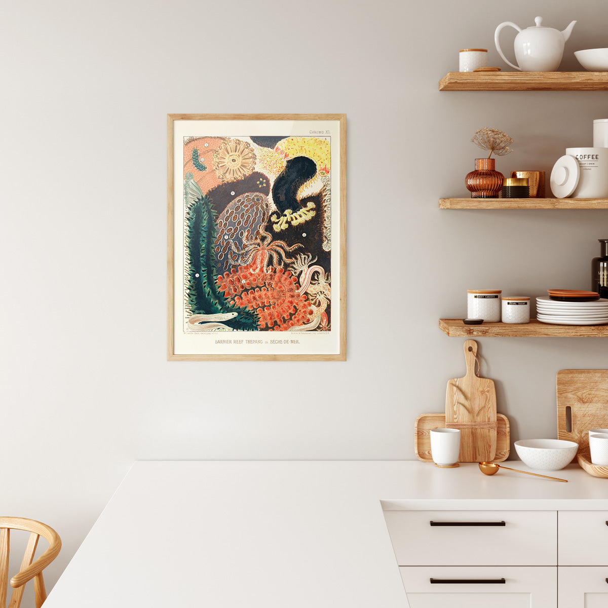 Plakat i træramme hængende i et moderne køkken med lyse træhylder og hvide køkkenredskaber.