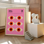 Bauhaus plakat med et geometrisk øje-design fra 1923, placeret på et trægulv ved siden af moderne skulpturer.