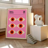 Bauhaus plakat med et geometrisk øje-design fra 1923, placeret på et trægulv ved siden af moderne skulpturer.