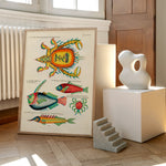 Plakat med farverige illustrationer af krabber og fisk, placeret på et gulv ved siden af moderne skulpturer og en radiator.