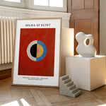 Hilma af Klint plakat med abstrakt design, placeret på et trægulv ved siden af en moderne skulptur.
