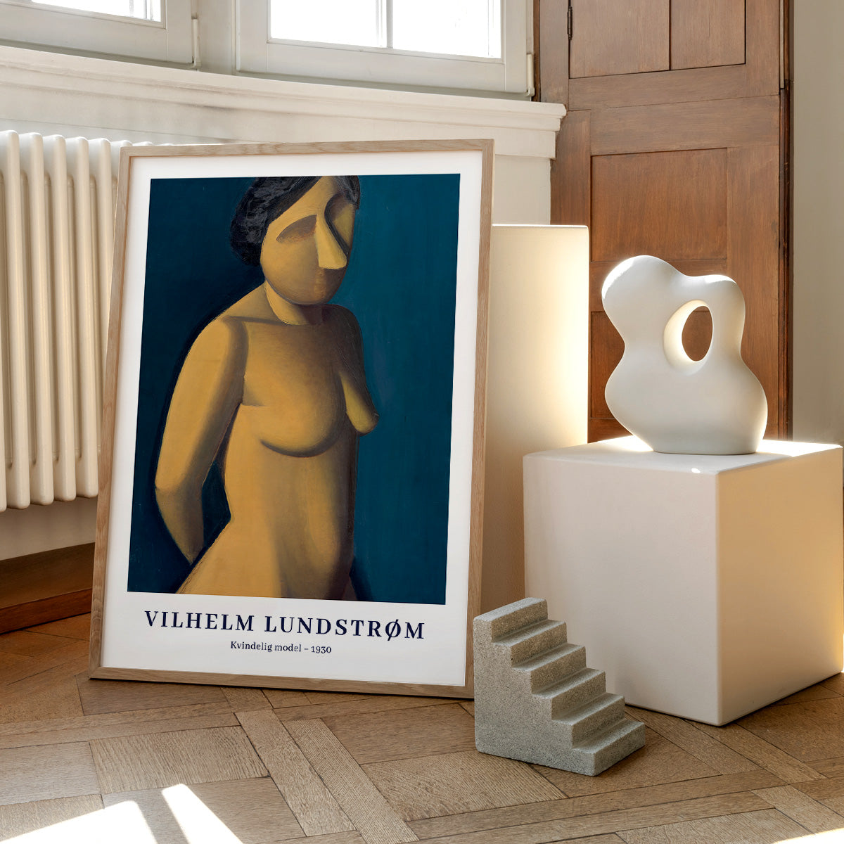 Plakat af Vilhelm Lundstrøm med titlen "Kvindelig model - 1930" placeret på et trægulv ved siden af en skulptur.