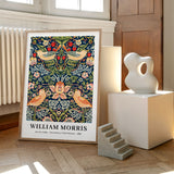 Plakat af William Morris med titlen "Strawberry Thief Pattern - 1883" placeret på et trægulv ved siden af en moderne skulptur og en lille trappe.