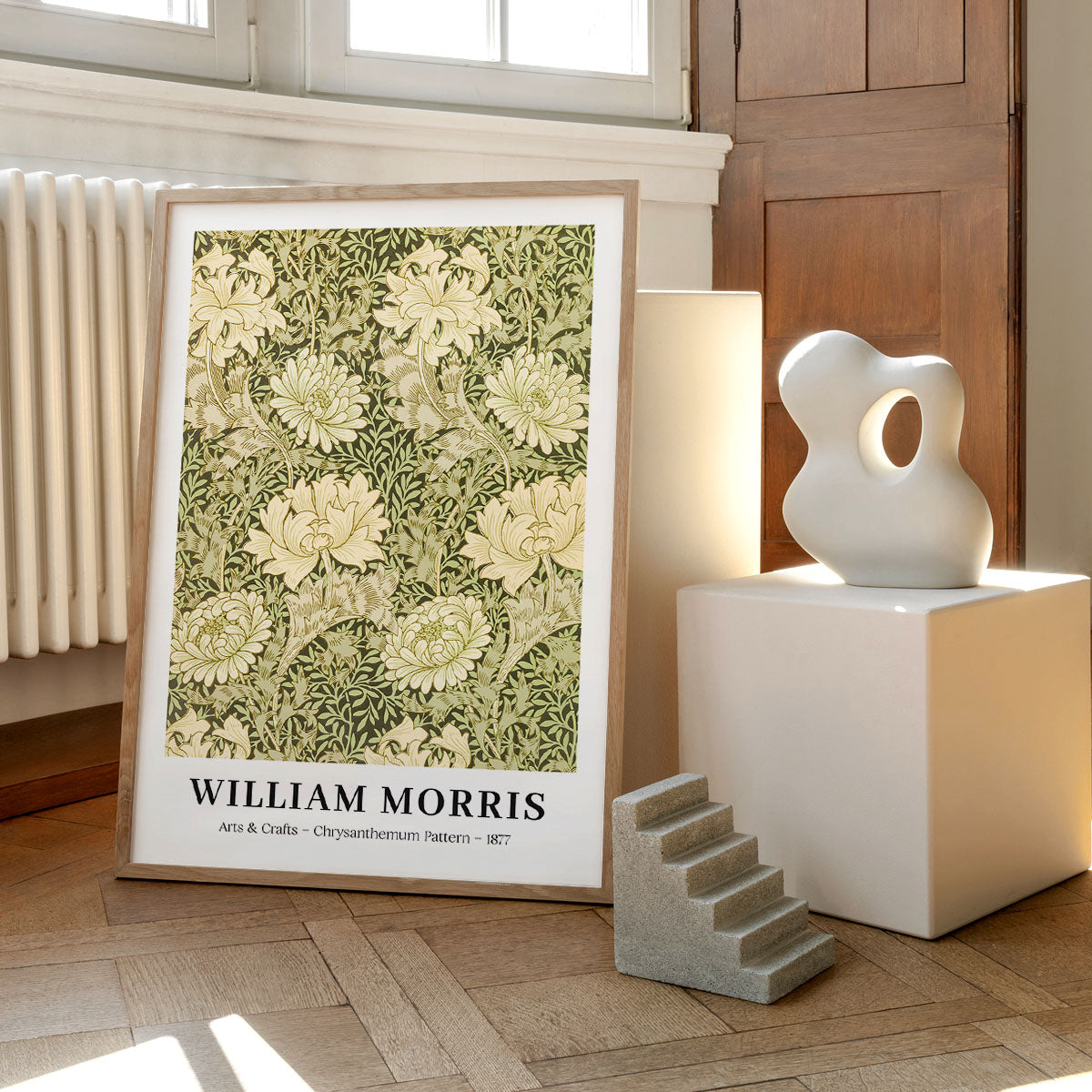 William Morris plakat med "Chrysanthemum Pattern" design fra 1877, placeret på et trægulv ved siden af moderne skulpturer.