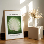 Ohara Koson plakat med påfugl, stående på gulv ved siden af en vase med tørrede blomster.