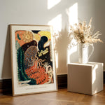 Plakat med farverigt undervandsmotiv, der står op ad en væg ved siden af en vase med tørrede blomster.