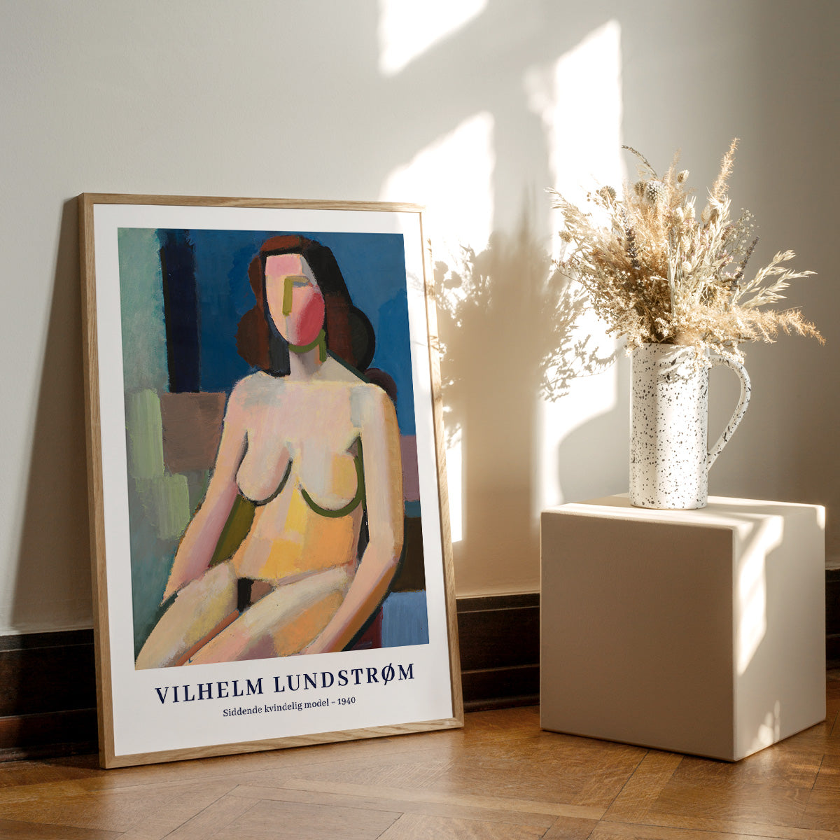 Vilhelm Lundstrøm plakat med abstrakt kvindefigur, placeret på gulv ved siden af en vase med tørrede blomster.