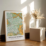 William Morris plakat med botanisk mønster, placeret på gulvet ved siden af en vase med tørrede blomster.
