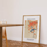 Plakat af Ohara Koson med en mejse på en gren, placeret på gulvet i en stue ved siden af et bord.