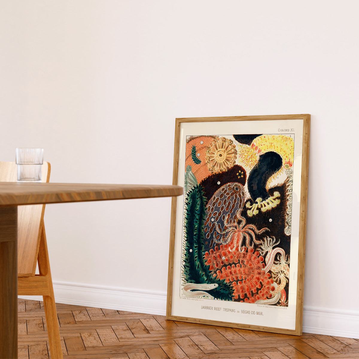 Plakat med farverigt undervandsmotiv, der viser forskellige havdyr og planter, placeret op ad en væg i en moderne stue.