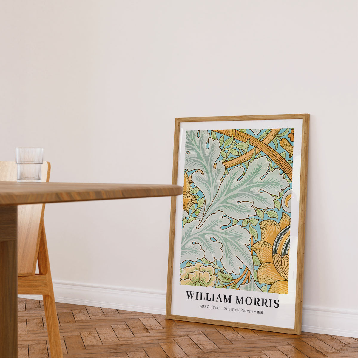Plakat af William Morris med botanisk mønster, placeret på gulvet i en lys stue ved siden af et træbord.