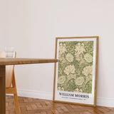 Plakat af William Morris med titlen "Chrysanthemum Pattern" fra 1877, placeret på gulvet i en stue ved siden af et bord.