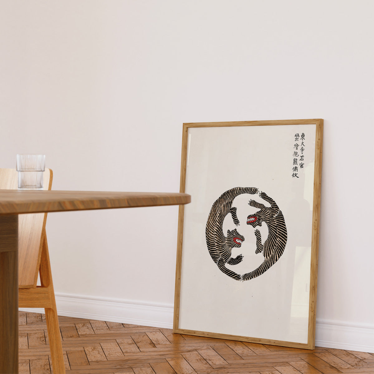 Plakat med et kunstnerisk tigerdesign i sort og hvid, placeret på gulvet ved siden af et træbord i en moderne stue.