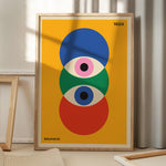 Bauhaus plakat med farverige geometriske former, stående på gulv med skygge fra vindue.