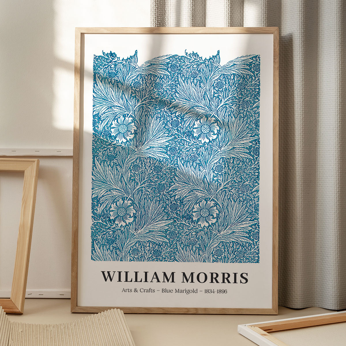 William Morris plakat med blå marigold design, stående på gulv med skygge fra vindue.