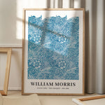 William Morris plakat med blå marigold design, stående på gulv med skygge fra vindue.
