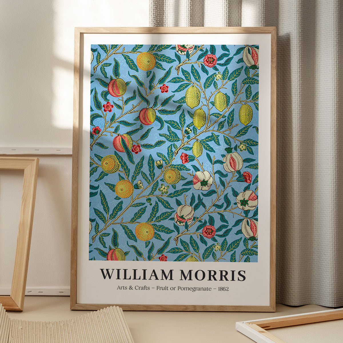 William Morris plakat med frugt- og granatæblemotiv, Arts & Crafts stil, 1862, stående på gulv med skygge fra vindue.