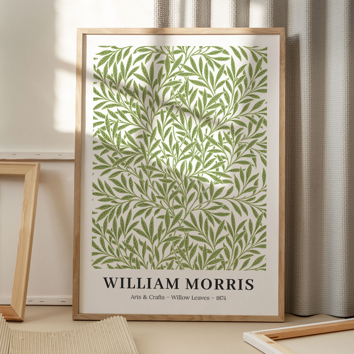 Plakat med grønne blade designet af William Morris, titlen "Willow Leaves", år 1874, placeret på et gulv med skygger fra et vindue.