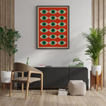 Plakat med geometrisk mønster af øjne i grønne og orange farver, hængende på en væg i en moderne stueindretning med planter og minimalistiske møbler.