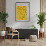 Plakat med gult mønster og japansk skrift hænger på en væg i en moderne stueindretning med planter og minimalistiske møbler.
