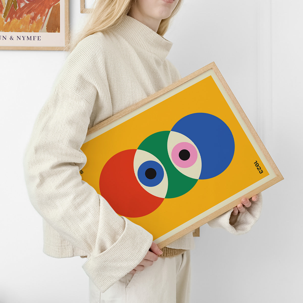 Plakat med farverige cirkler i Bauhaus-stil, holdt af en person i lyse tøj.