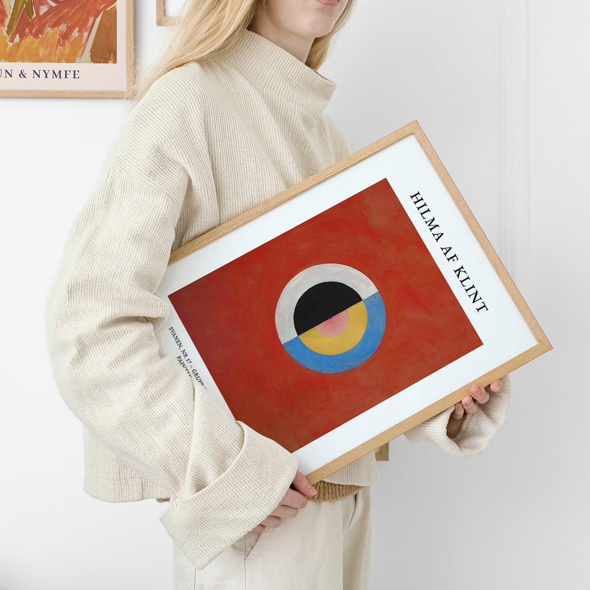 Hilma af Klint plakat med abstrakt design i røde, blå og gule farver, holdt af en person i lys tøj.