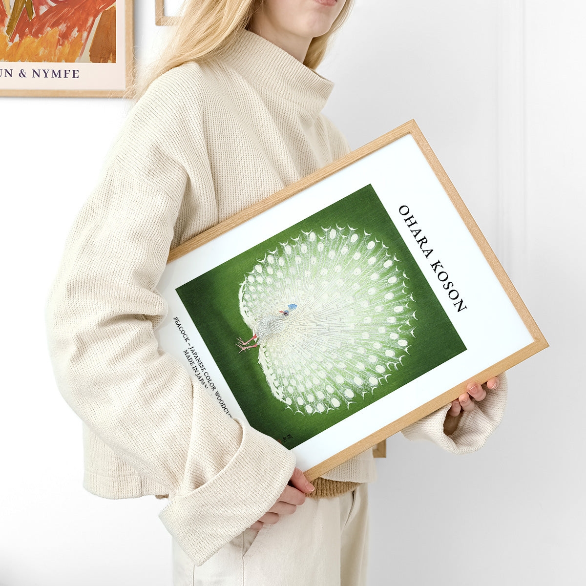 Ohara Koson plakat med hvid påfugl på grøn baggrund, holdt af person i beige tøj.