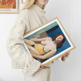 Plakat af en kvinde, der holder en indrammet kunstplakat med et abstrakt motiv i lyse farver.