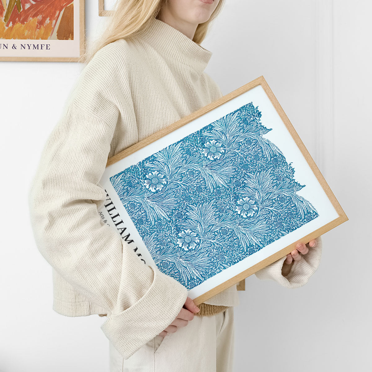 Kvinde holder en plakat med et blåt, blomstret mønster i en træramme.