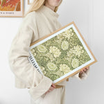 Kvinde holder en plakat med et botanisk design af William Morris.