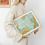 Kvinde holder en plakat med et botanisk design af William Morris.