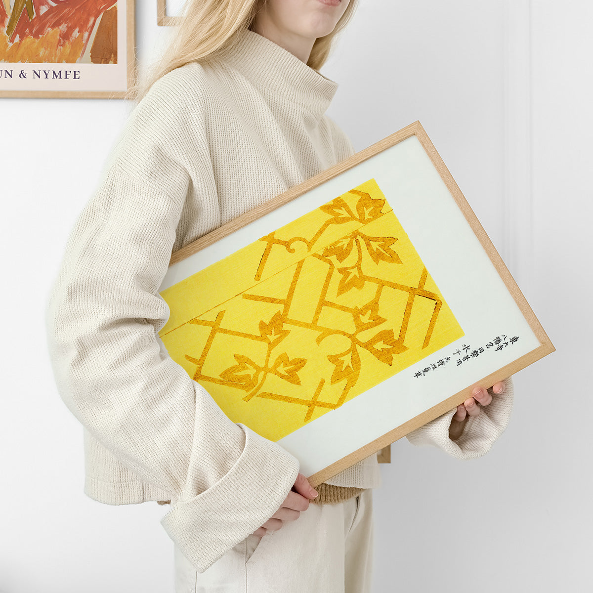 Plakat med gult og orange bladmønster, holdt af person i lys trøje.