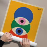 Plakat med geometrisk design i Bauhaus-stil, viser tre overlappende cirkler i blå, grøn og pink på gul baggrund, med årstallet 1923 i hjørnet.