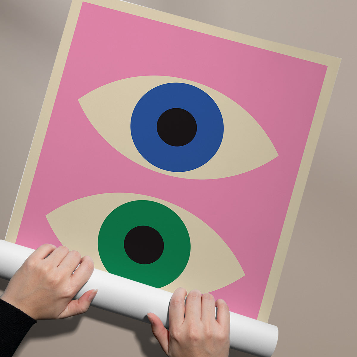 Plakat med to stiliserede øjne i blå og grøn på en lyserød baggrund, rullet op af en person.