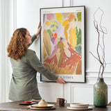 Kvinde hænger Faun og Nymfe kunstplakat af Edvard Weie op i en spisestue.